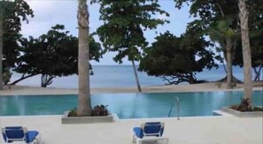 A pool area with lounge chairs, a view of the beach, and palm trees. - Negril Beachhouse




 (Negril)