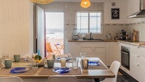 Una cucina moderna con zona pranzo, caratterizzata da un'ampia finestra, una macchina del caffè e vista sull'esterno.