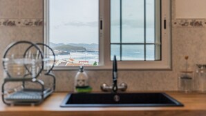 Una cucina con vista sull'oceano attraverso una finestra.