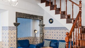 Un soggiorno con un divano blu, un tavolino rotondo, una lampada da terra e una scala in legno.