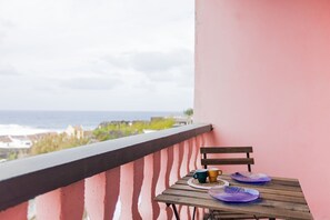 Un balcon avec une table et des chaises, offrant une vue sur la côte.
