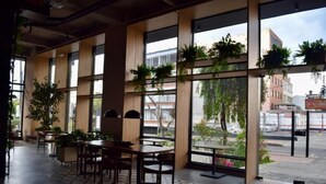 Un espace intérieur vaste et lumineux, avec de grandes fenêtres, des tables et des chaises en bois.