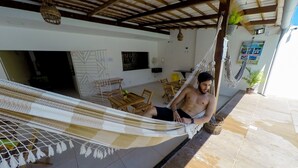 A hammock in a room with a tiled floor, wooden furniture, and a ceiling with exposed beams. - Pousada Barra Grande (Maragogi)