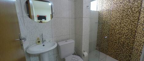Et badeværelse med toilet, håndvask og brusebad.