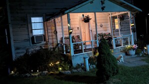 Una casa con porche, un pequeño jardín y un perro.