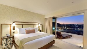 A hotel room with a large bed, a nightstand, a chair, and a balcony with a city view. - Beach Access!! Beautiful Oceanfront Resort! Room upgrades available!  (Cabo San Lucas)