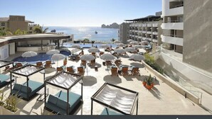 A rooftop pool area with sun loungers and umbrellas, overlooking the sea. - Beach Access!! Beautiful Oceanfront Resort! Room upgrades available!  (Cabo San Lucas)