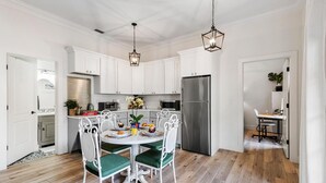Una cocina moderna con muebles blancos, un refrigerador de acero inoxidable y un comedor con una mesa redonda y sillas.