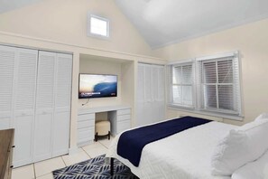 A bedroom with a bed, a TV, a desk, and a wardrobe.