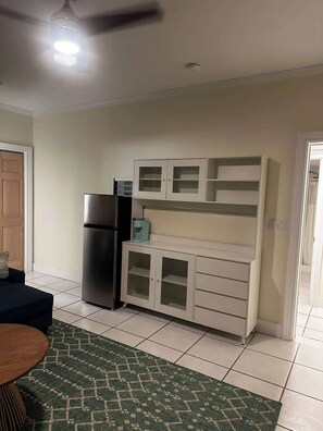 A kitchen with a refrigerator, a microwave, and a cabinet with drawers.