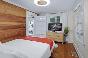 A bedroom with a bed, a television, a dresser, and a window.
