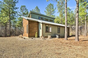 A two-story house with a wooden exterior and a gravel driveway, surrounded by trees.