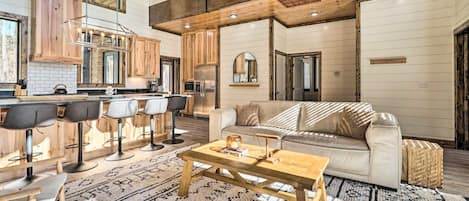 A spacious living area with a sofa, coffee table, and bar stools.