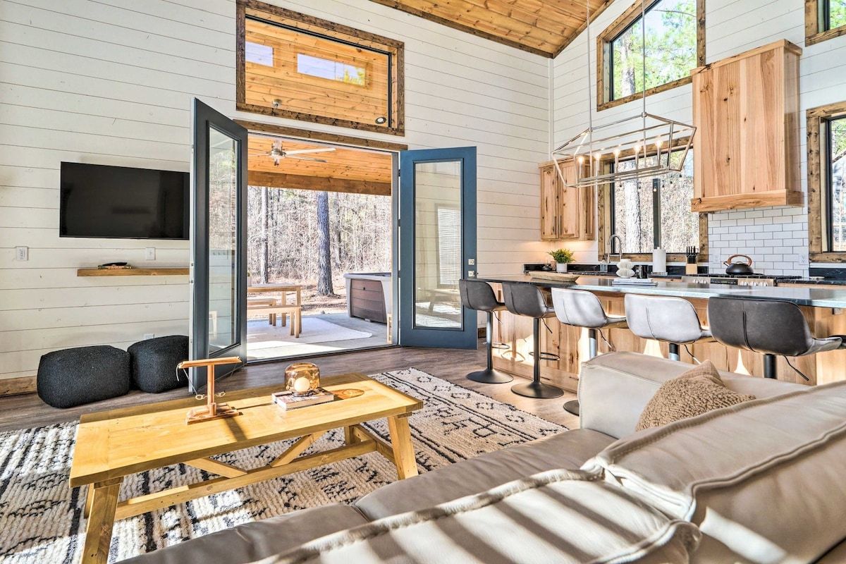 A modern interior with a wooden ceiling, a kitchen with bar stools, a dining area, and a large window.