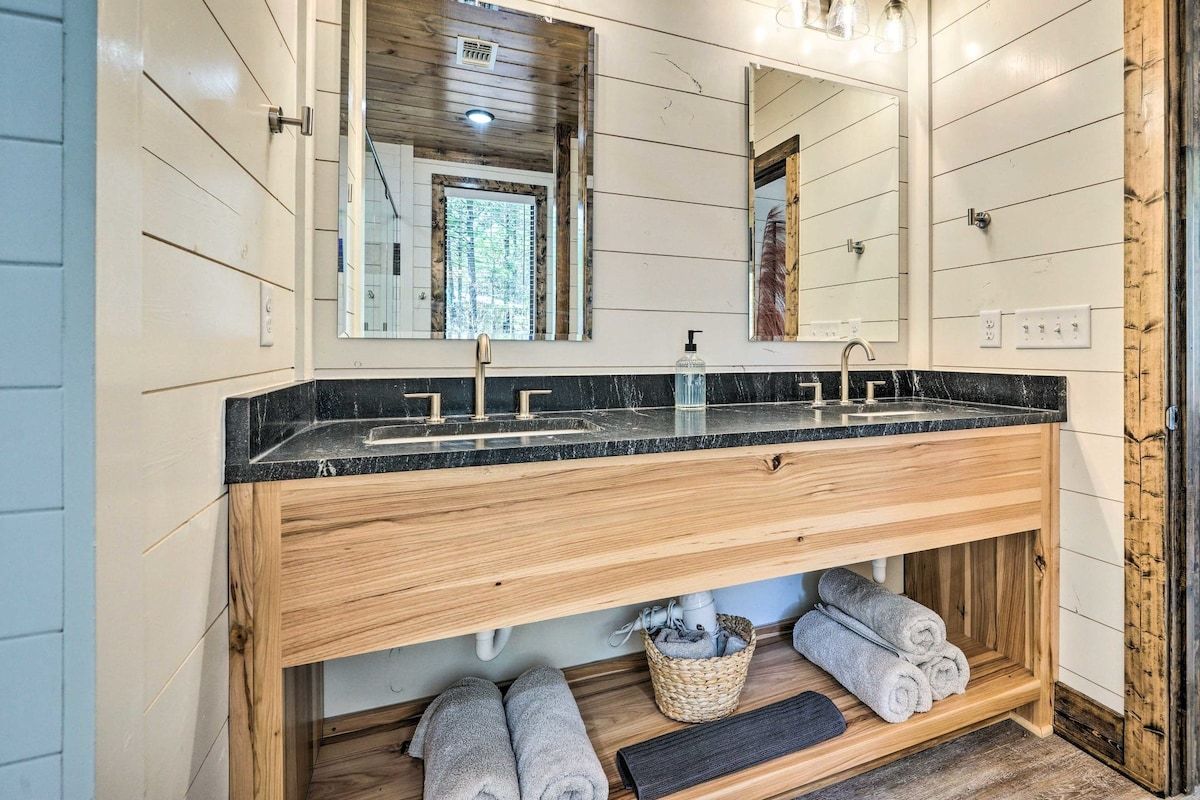 A bathroom with a wooden vanity, a large mirror, and a black countertop.