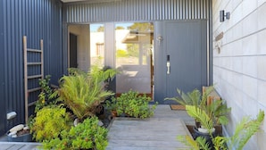 A modern house with a skylight, a wooden deck, and various plants. - The Sweet Spot Taupo (Taupō)