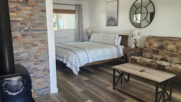 Ein gemütliches Zimmer mit Bett, Sofa, Tisch, Kamin und einem Fenster mit Vorhängen.