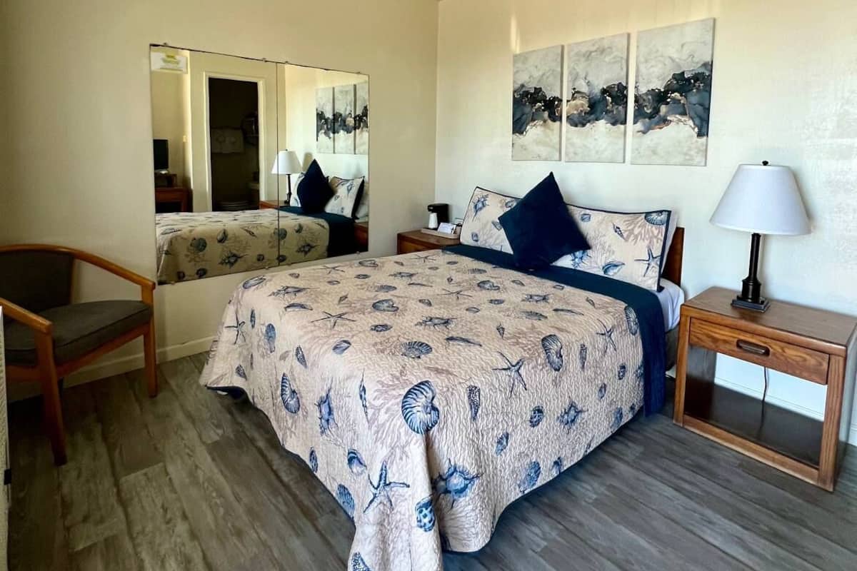 A bedroom with a bed, a chair, a nightstand, and a lamp.