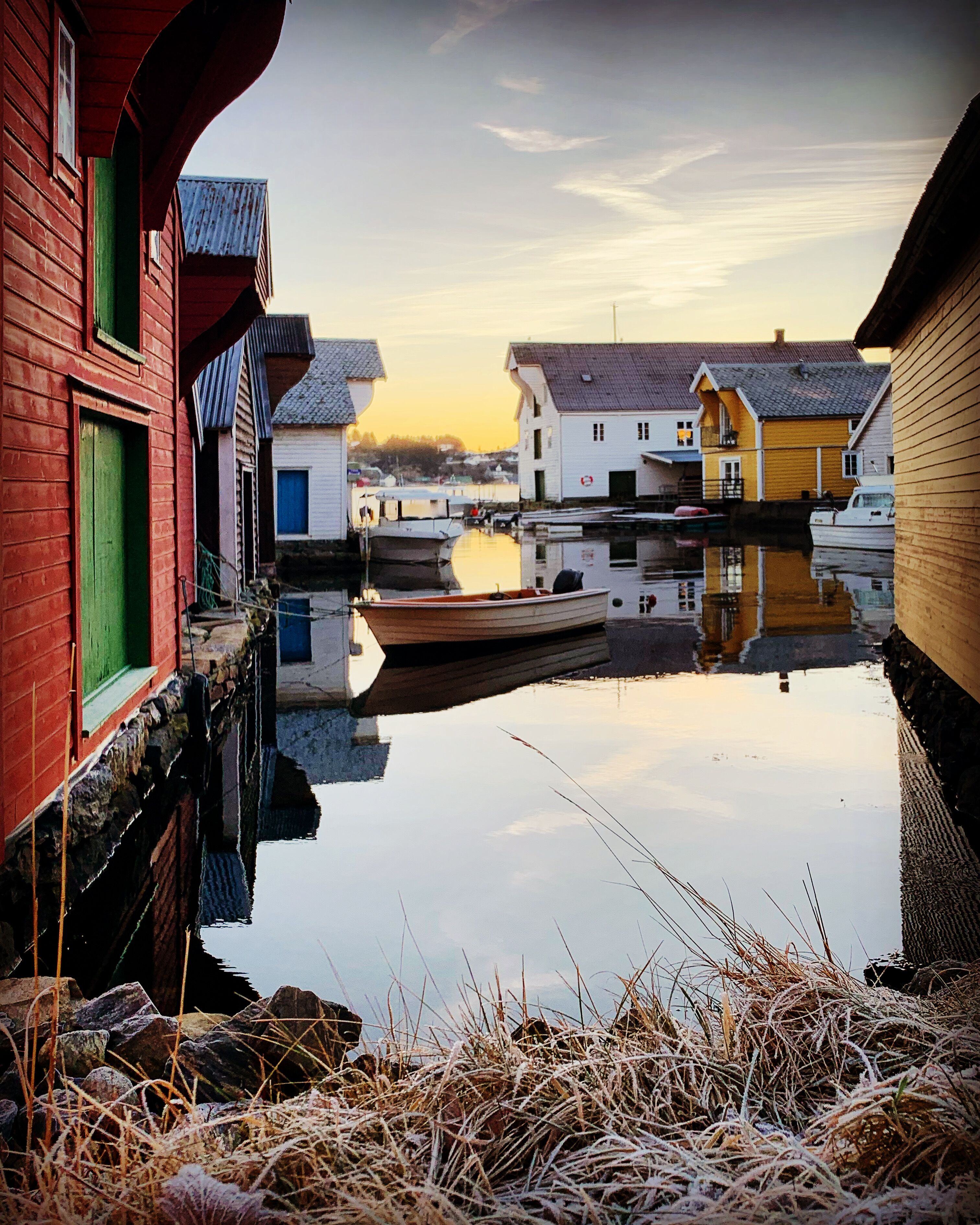 A canal with boats, wooden houses, and a clear sky.