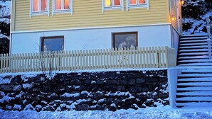 Ein zweistöckiges Haus mit verschneitem Dach und einem weißen Zaun.