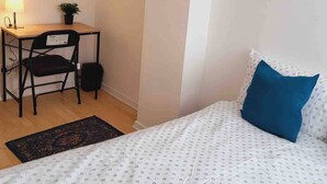 Une chambre à coucher avec un lit, un bureau, une chaise et une petite plante en pot.