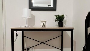 Un bureau avec une lampe, un petit objet décoratif et une plante en pot.