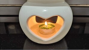 Un porte-bougie en forme de cœur avec une bougie allumée, posé sur un comptoir noir.