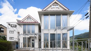 A modern two-story residential building with large windows and a prominent X-shaped design on the facade. - Wakoso Harmonious Light South (Hakone)
