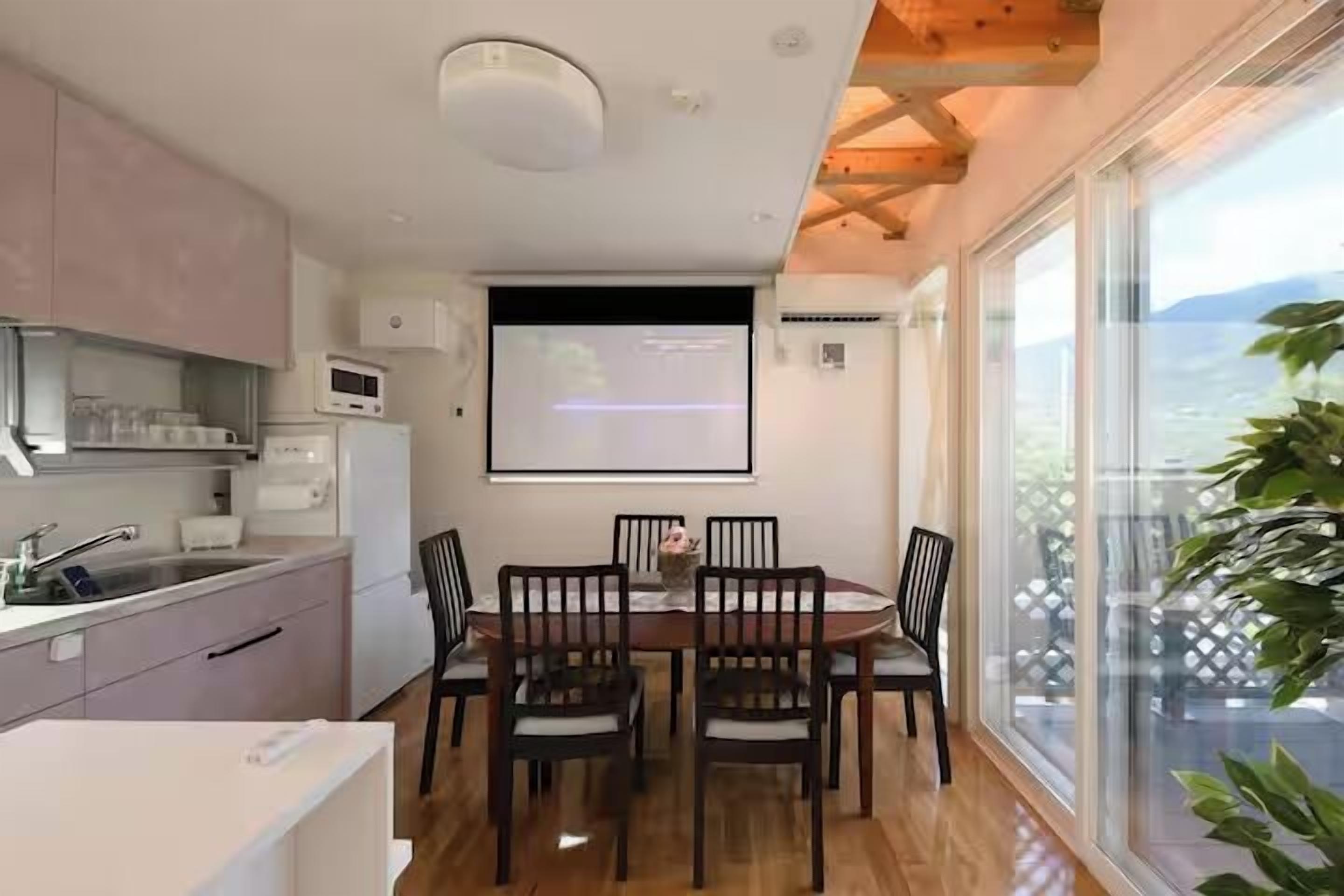 A modern kitchen with a dining area, large windows, and a view of the outdoors.