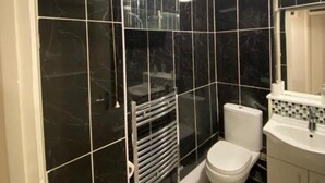 A bathroom with black marble tiles, a white toilet, a white sink, and a mirror above the sink. - Room in Apartment - Normanton - Deluxe Double Room (Birmingham)
