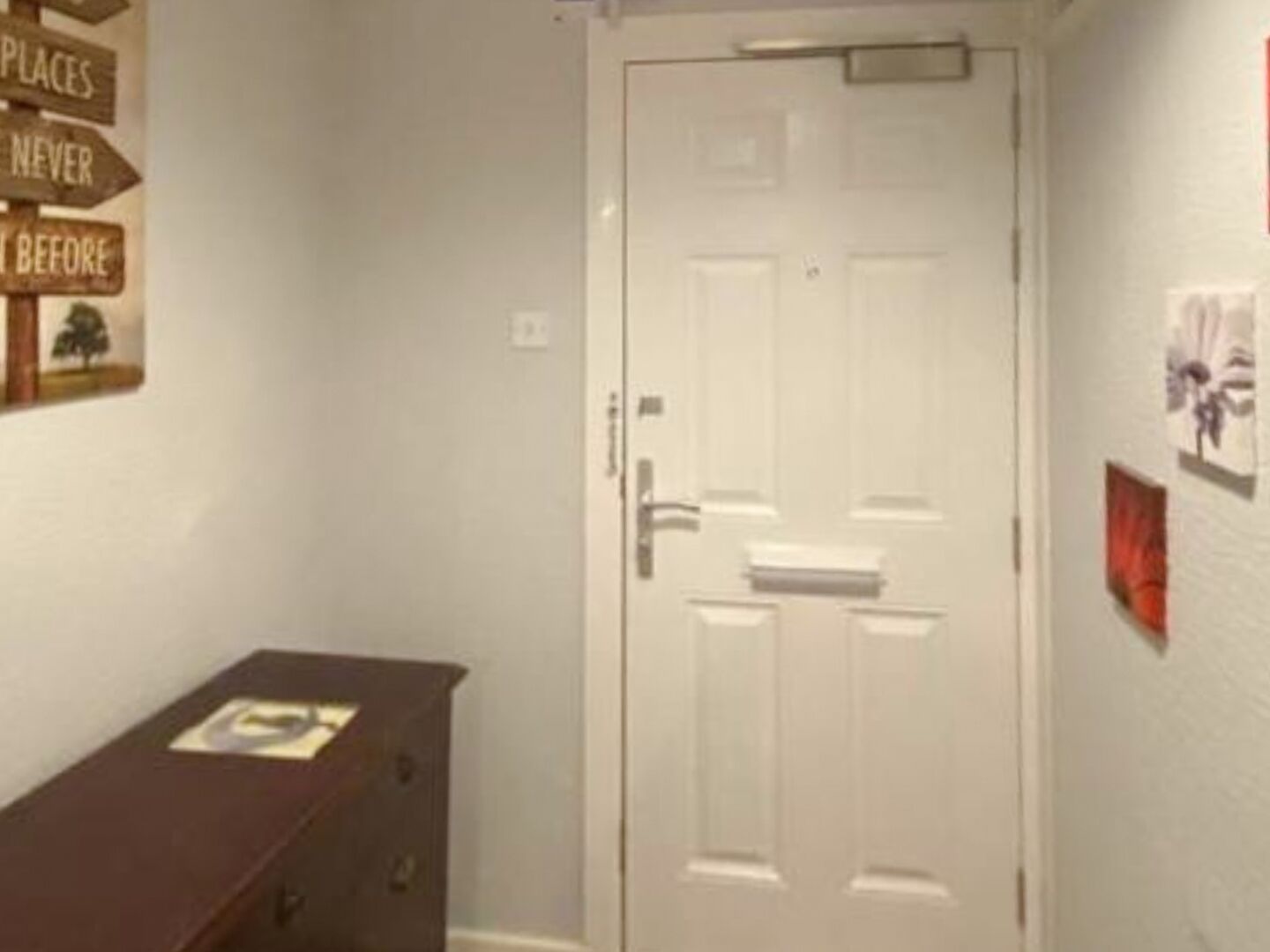 Ein Flur mit einer weißen Tür, einem Holzschrank und einer Wand mit Schildern.