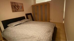 A bedroom with a bed, a wardrobe, and a wall decoration. - Room in Apartment - Normanton - Deluxe Double Room (Birmingham)