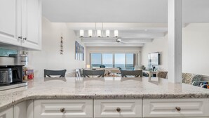 Una cocina moderna con armarios blancos, encimera de granito y vistas al océano.