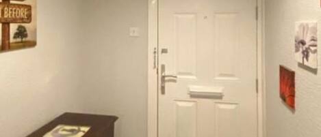 A hallway with a white door, a wooden cabinet, and a wall with signs.