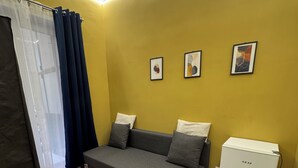 A room with a grey sofa, a white mini-fridge, and three framed pictures on the wall. - Vomero Suite and deluxe room (Naples)