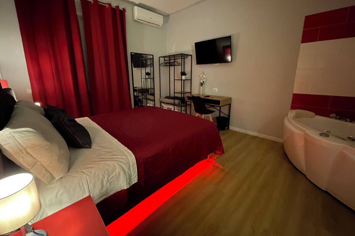 A hotel room with a bed, a desk, a chair, a TV, and a bathtub.