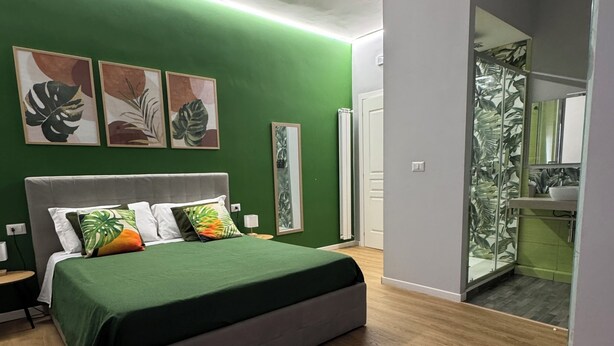 A modern bedroom with a bed, green walls, and a wooden floor. - Vomero Suite and deluxe room (Naples)