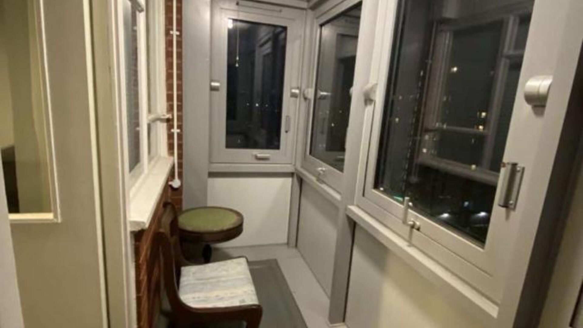 A narrow hallway with a small wooden bench and a window.