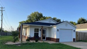 A single-story house with a front garage, a small porch, and a well-maintained lawn.