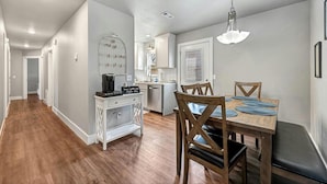 A modern kitchen with white cabinets, a microwave, and a coffee machine.