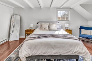 Ein Schlafzimmer mit einem Bett, Nachttischen, einem Spiegel und einem Fenster.