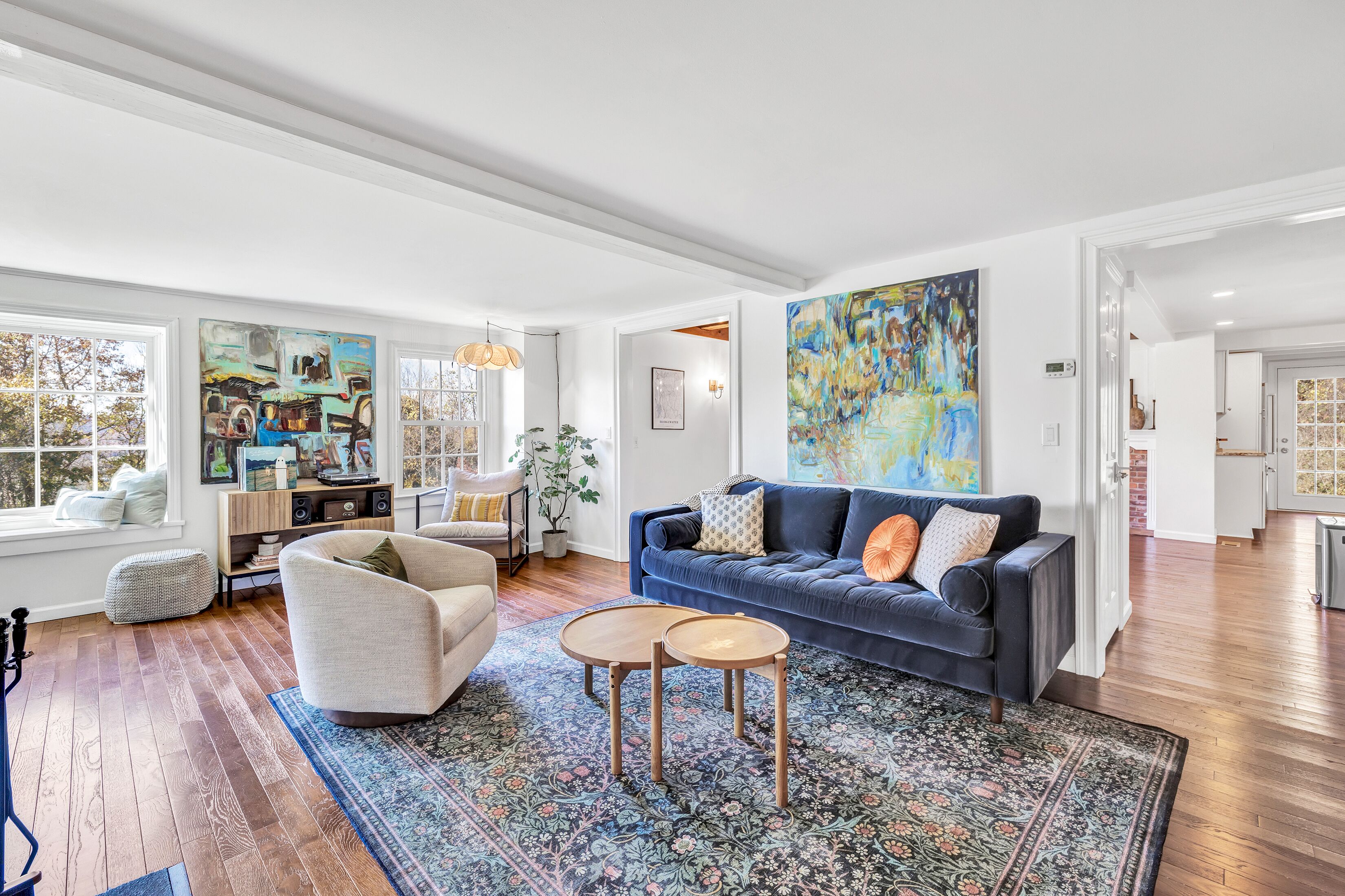 A spacious living room with a blue sofa, a beige armchair, and a patterned rug.