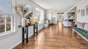 Un salon spacieux doté d’un parquet, d’un canapé vert et d’un coin repas avec une table et des chaises.