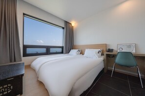 Habitación de hotel con un ventanal grande, una cama, un escritorio con silla y un teléfono.