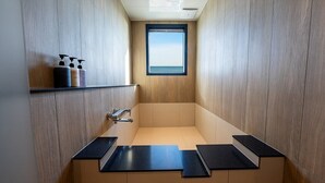 Une salle de bain moderne avec un intérieur en bois, une fenêtre intégrée et un plan de toilette noir.
