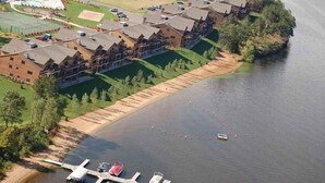 A lakeside lodge with a dock, a swimming pool, and a tennis court.