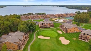 A golf course with bunkers and a large building complex with multiple stories and balconies.