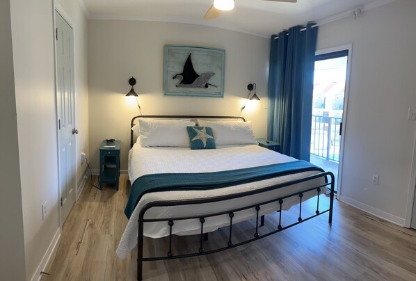 A bedroom with a bed, a nightstand, a wall-mounted lamp, and a window with curtains.