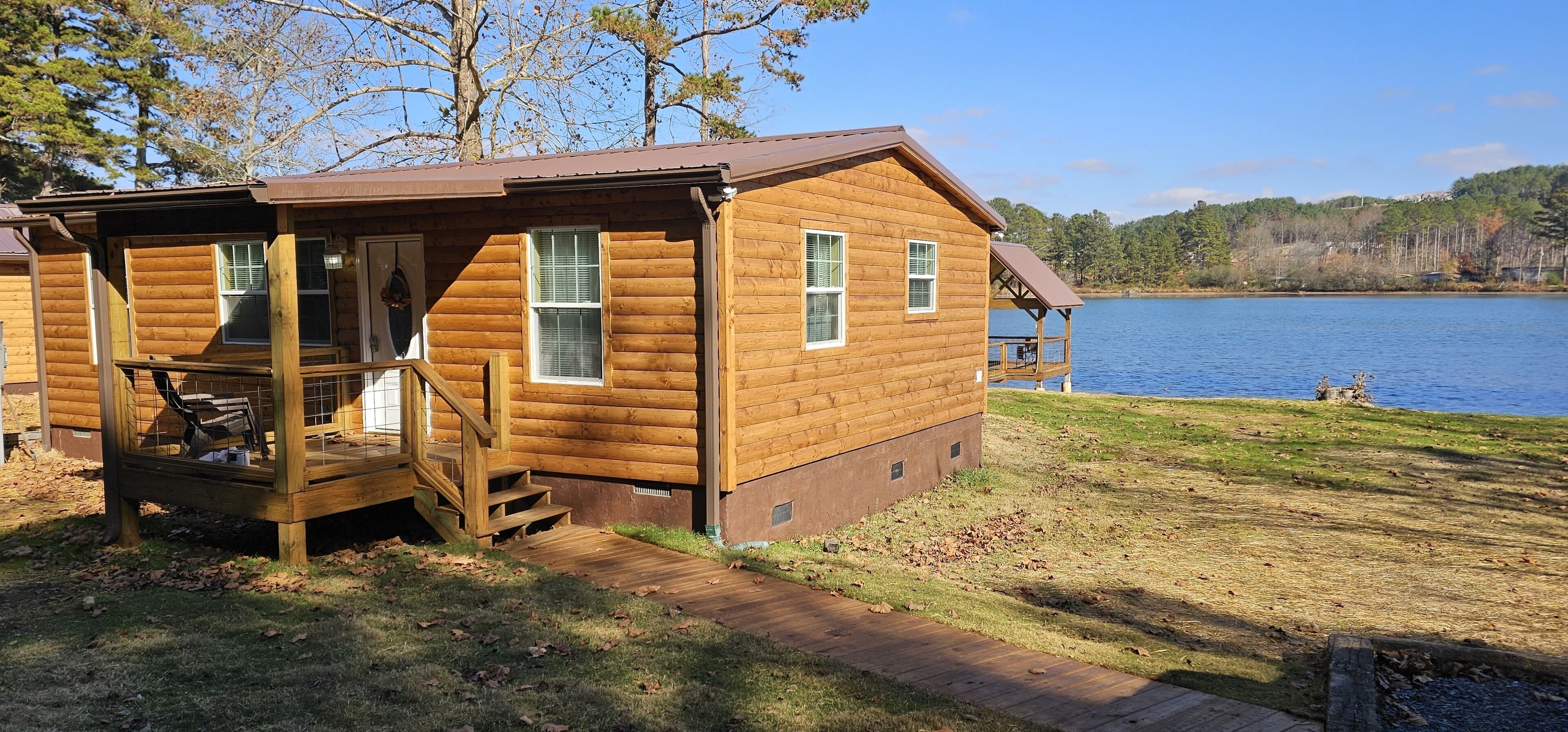 A wooden cabin with a porch and a view of a lake.