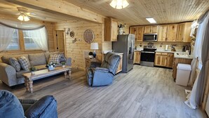 Een gezellig cabin interieur met een zithoek, bank, voetenbankje en een keuken.